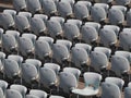 Rows of numbered empty plastic seats at an open-air amphitheater. many audience open theater seats