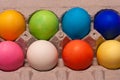 2 rows of orange, green, blue, pink, white, red and yellow dyed eggs in cardboard egg carton Royalty Free Stock Photo