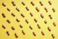 Rows of peanuts arranged on yellow background