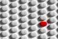 Rows of pills on a white background. One pill stands out with its red color Royalty Free Stock Photo