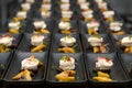 Rows of prepared appetizers from feta cheese and rhubarb with sprout garnish arranged on black plates, menu course of a festive Royalty Free Stock Photo