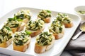 rows of spinach and artichoke bruschetta on a white tray with a silver spoon