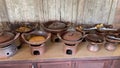 Rows of tiny antique clay cooking utensils on antique wooden tables