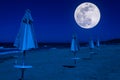 rows of umbrellas and deck chairs on the beach at night Royalty Free Stock Photo