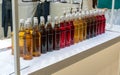 Rows of variety flavored syrup in plastic bottles arranged on white shelf