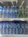 Rows of various types and brands of mineral water products on refrigerator shelves at the Indomaret Indonesia minimarket