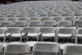 Rows of white folding chairs at a concert, wedding, festival or gathering