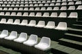 Rows of white plastic armchairs in an open summer concert hall