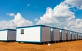 Rows of white plastic house boxes under a bright cloudy sky