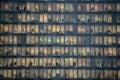 Rows of windows with people working in the interior of an office building at night in Milan, Italy