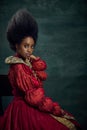 Royal Elegance. Portrait of young, beautiful african woman, medieval princess in vintage dress sitting, posing against