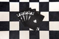 Royal flush in clubs on black cards on chessboard