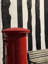 Royal mail post box against black and white striped wall