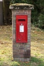 A royal mail post box in a brick pillar on the green.