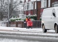 Royal mail post man Single lone delivering letters walking to work during winter blizzard and heavy snowstorm wrapped up warm mask