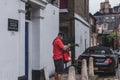 Royal Mail postman with a messenger bag delivering mail in London