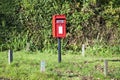 Royal Mail red pillar postbox hidden in green park