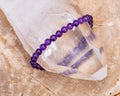 Royal purple Amethyst bead bracelet wrapped around Lemurian rainbow quartz point from Brazil on Natural Polished Petrified wood