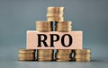 RPO - acronym on a wooden bar against the background of stacks of coins