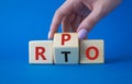 RPO vs RTO symbol. Businessman hand turns wooden cubes and changes the word RTO to RPO. Beautiful blue background. business