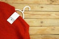 Rred sweater on hangers on wooden background with Zara tag with copy space, winter sales concept, closeup