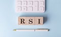 RSI word on wooden block with pen and calculator on blue background