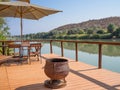 Ruacana, Namibia - July 22, 2015: Wooden terrasse with chairs, umbrealla, table and cast iron pot at Kunene River Royalty Free Stock Photo