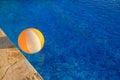 Rubber air yellow white inflatable ball and toy for swimming pool in transparent blue water. Multi-colored beach ball floating.