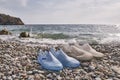 Rubber blue women& x27;s and grey men& x27;s slippers for swimming on a pebble beach Royalty Free Stock Photo