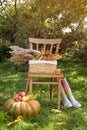 Rubber boots, chair, pumpkin and apples on green grass in park. Autumn atmosphere