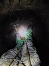 Rubber boots of a protective suit and camouflage pants in the light of a flashlight