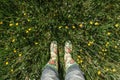 Rubber boots on a spring background. Meadow full of fresh spring flowers. Young woman in rain boots walking in wet grass Royalty Free Stock Photo