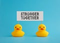 Rubber ducks carry a signboard with the word stronger together. Teamwork, cooperation, togetherness or collaboration Royalty Free Stock Photo