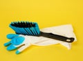 Rubber glove and black plastic brush for cleaning the house on a yellow background Royalty Free Stock Photo