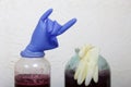 A rubber glove on a can of fermenting grape wine. Inflated from fermentation gases. The fingers are bent in a goat gesture. Near a