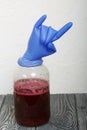 A rubber glove on a can of fermenting grape wine. Inflated from fermentation gases. The fingers are bent in a Sign of the horns.
