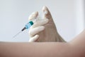 A rubber gloved hand holds a syringe filled with a blue liquid and gives an injection to the other hand Royalty Free Stock Photo