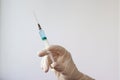 A rubber gloved hand holds a syringe filled with a blue liquid needle up Royalty Free Stock Photo