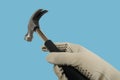 rubber-handled hammer with nail puller, round head for fine work in hand of builder in glove, manual universal percussion tool for Royalty Free Stock Photo