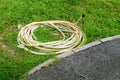 A rubber pile hose on green grass in the garden beside a walkway Royalty Free Stock Photo