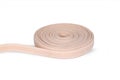 Rubber roll. Beige elastic band roll for sewing close-up. Fabric tape for needlework of the cloth on white background.Cloth ribbon