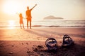 Rubber slippers on the beach with freedom father and daughter standing, arms outstretched and watching the sunrise Royalty Free Stock Photo