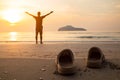 Rubber slippers on the beach with freedom the man standing, arms outstretched and watching the sunrise Royalty Free Stock Photo
