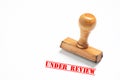 Rubber stamp with under review sign on white background