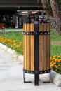 Rubbish bin in the park in summer. Turkish wooden trashcan outdoor, urn for garbage, wastebasket and grass with flowers Royalty Free Stock Photo