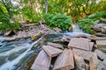 Rubble of cement blocks surrounding river with small waterfall and lush green forest Royalty Free Stock Photo