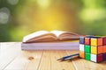 Rubik cube, book, pen and pencil in wooden table on nature