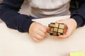 Rubik`s cube in children`s hands, closeup, white wooden background. Boy holding Rubik`s cube and playing with it