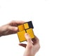 Rubik`s cube in the hands of a child, close-up, top view, white wooden background. A girl holds a Rubik`s cube and plays with it.