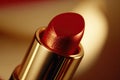 Ruby red lipstick on golden background. Beauty makeup cosmetics for lips. Glamourous fashion tube.